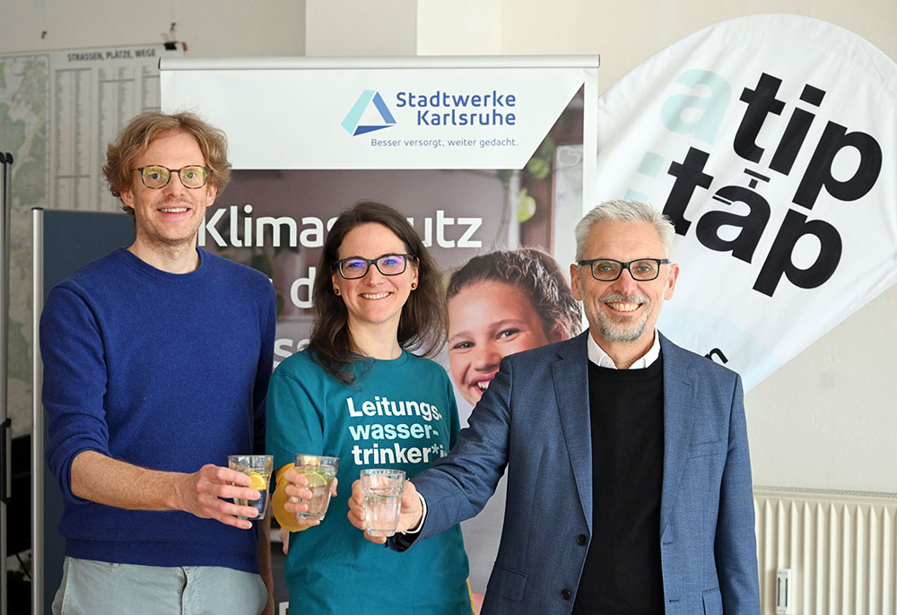 Thomas Frank, Nadine Bolch und Matthias Maier halten symbolisch ein Glas Wasser in die Kamera